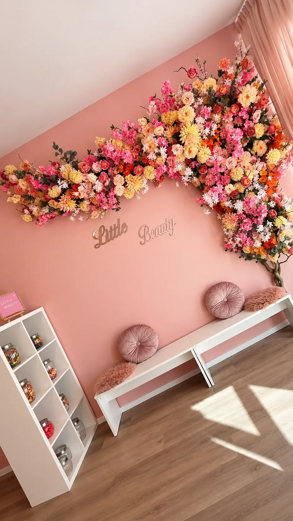Rosa Wand mit Blumenwand, Little-Beauty-Schriftzug, Sitzbank mit Kissen und Candy-Regal im Salon in Düsseldorf